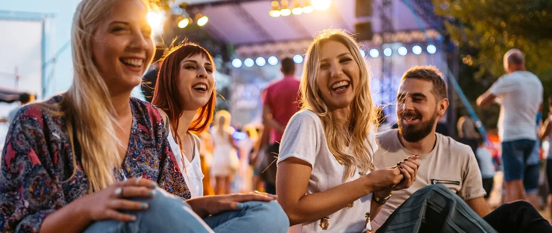 Junge Leute die auf einer Veranstaltung fröhlich im Scheinwerferlicht feiern.