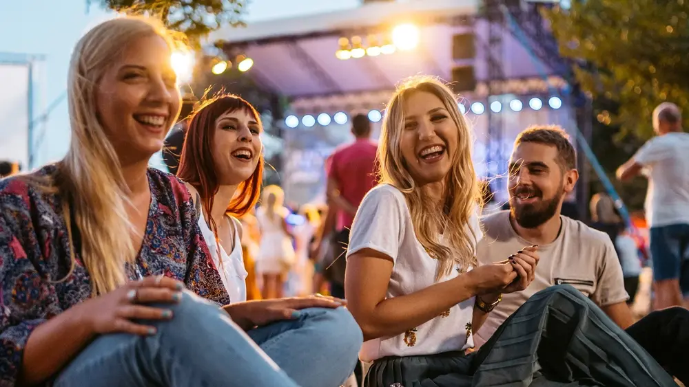 Junge Leute die auf einer Veranstaltung fröhlich im Scheinwerferlicht feiern.