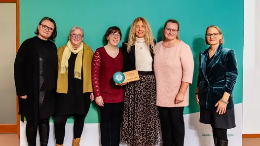 Eine Gruppe aus sechs Personen steht vor einer großen Werbewand von Westfalen Weser