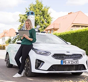 GeoScan Straßenerfassung auf dem Tablet Eine Frau lehnt mit einem Tablet an dem GeoScan Fahrzeug