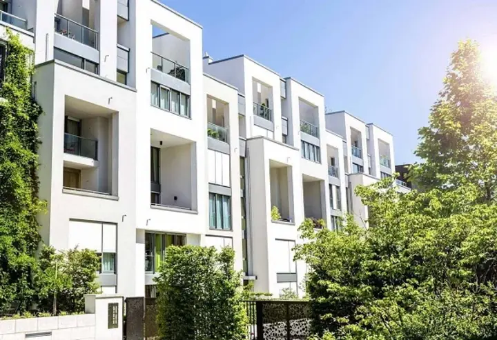 Moderne Mehrfamilienhäuser mit viel Grün bei Sonnenschein und wolkenfreiem Himmel