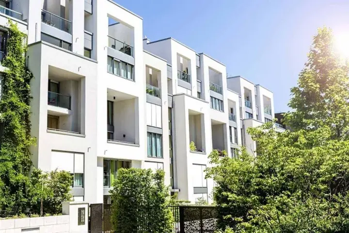 Moderne Mehrfamilienhäuser mit viel Grün bei Sonnenschein und wolkenfreiem Himmel