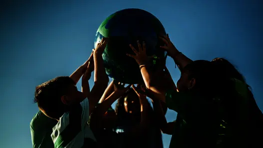 Kinder halten Ball als Erdkugel hoch