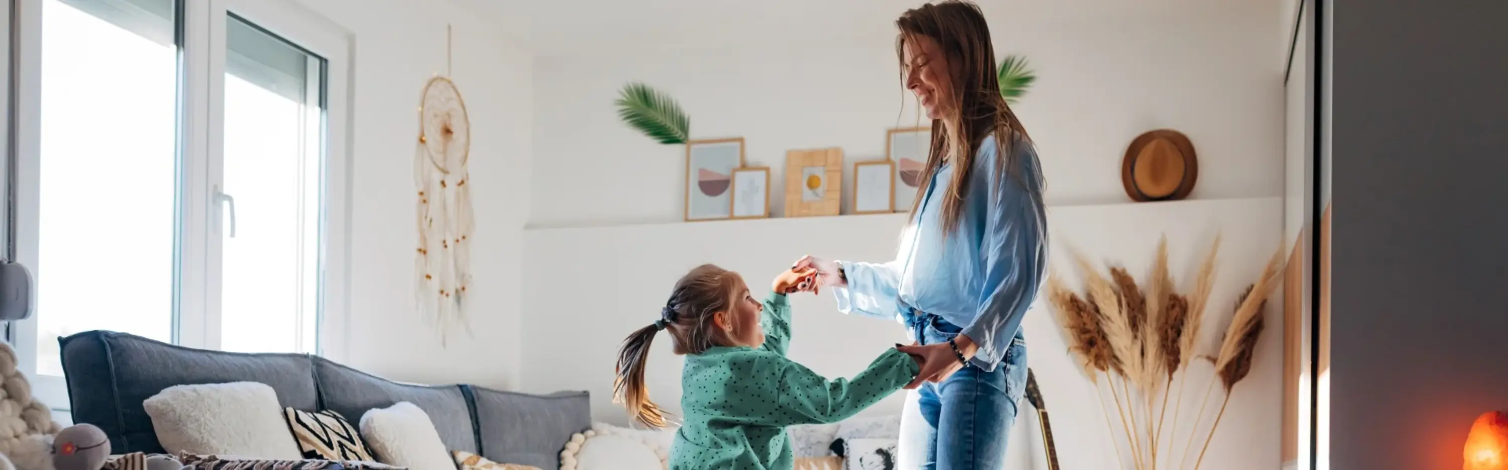 Eine Mutter tanzt mit ihrer Tochter in einem schön eingerichteten Wohnzimmer