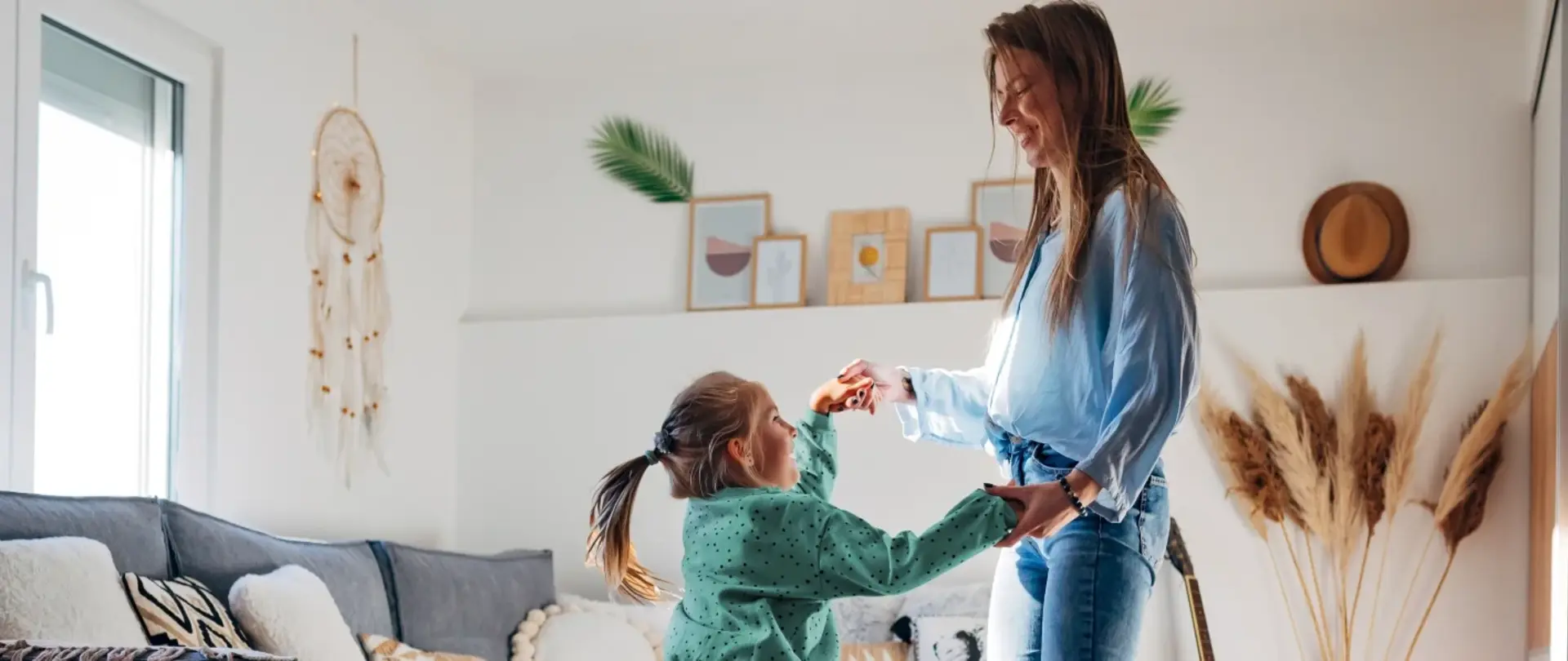 Eine Mutter tanzt mit ihrer Tochter in einem schön eingerichteten Wohnzimmer