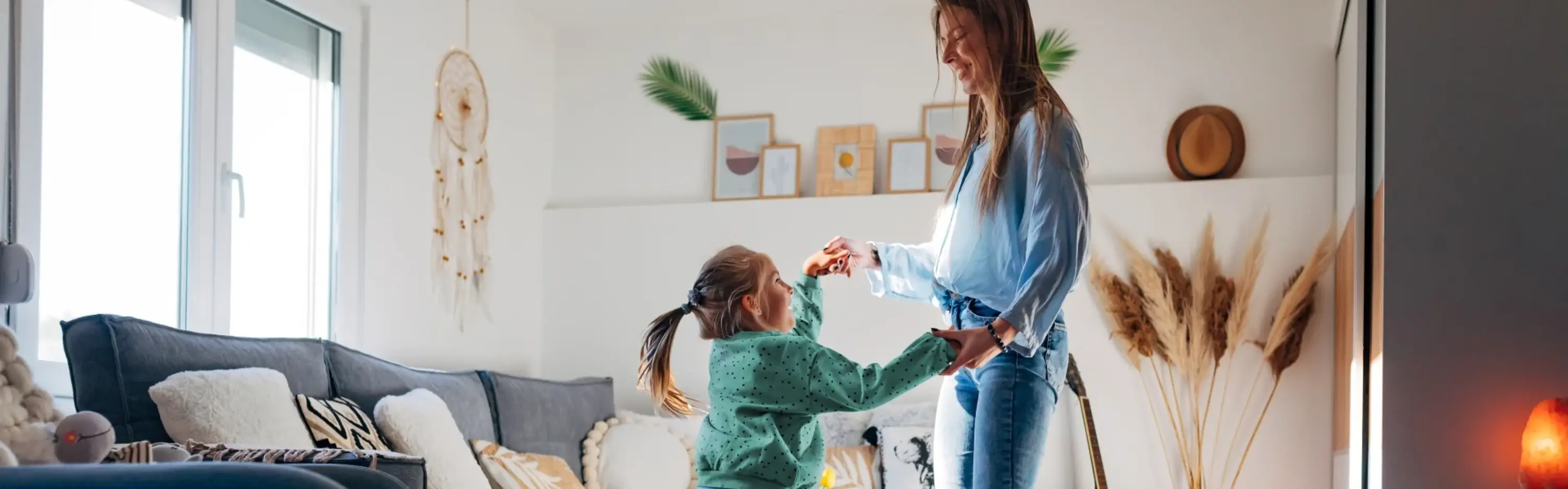 Eine Mutter tanzt mit ihrer Tochter in einem schön eingerichteten Wohnzimmer