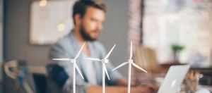 Mann am Schreibtisch mit Windradmodellen
