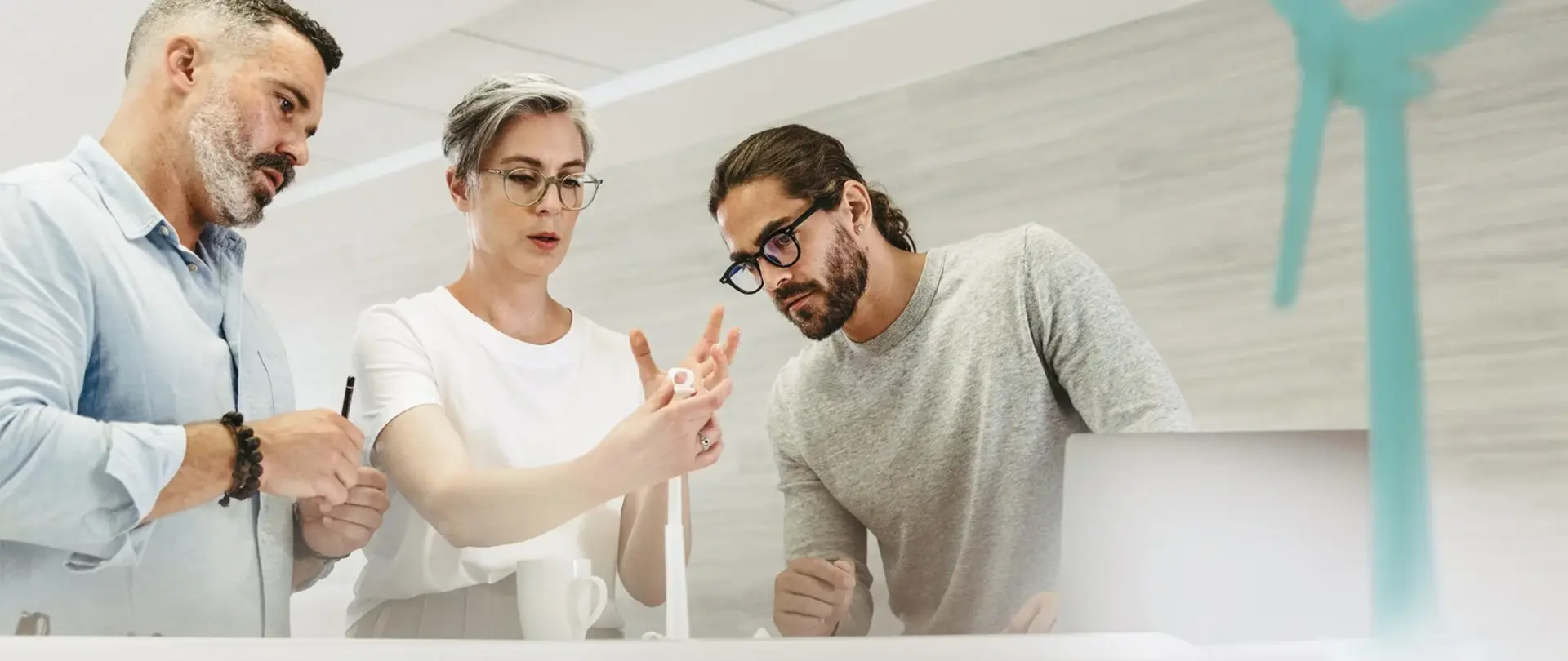 Ein Team von Mitarbeitenden diskutiert über ein Windradmodell
