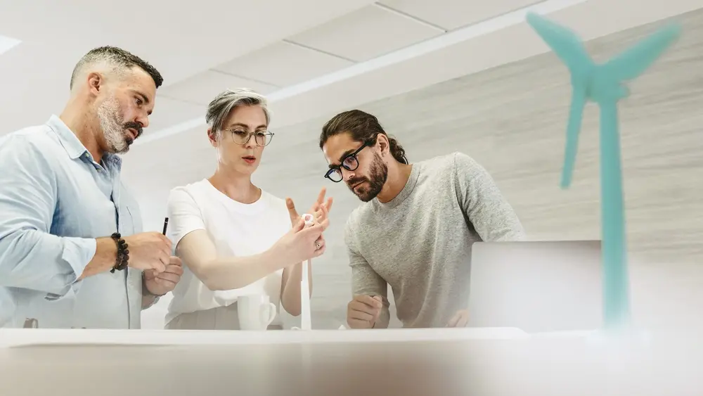 Ein Team von Mitarbeitenden diskutiert über ein Windradmodell
