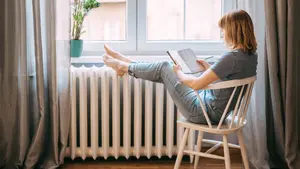 Eine Frau sitzt an einer Heizung