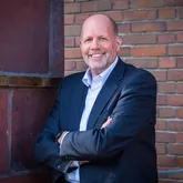 Stefan Freitag, Geschäftsführer der Energieservice Westfalen Weser, steht vor dem Firmengebäude und lächelt in die Kamera.