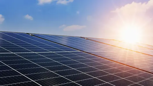 Eine große Fläche von Solarmodulen absorbiert Sonnenlicht unter klarem Himmel.