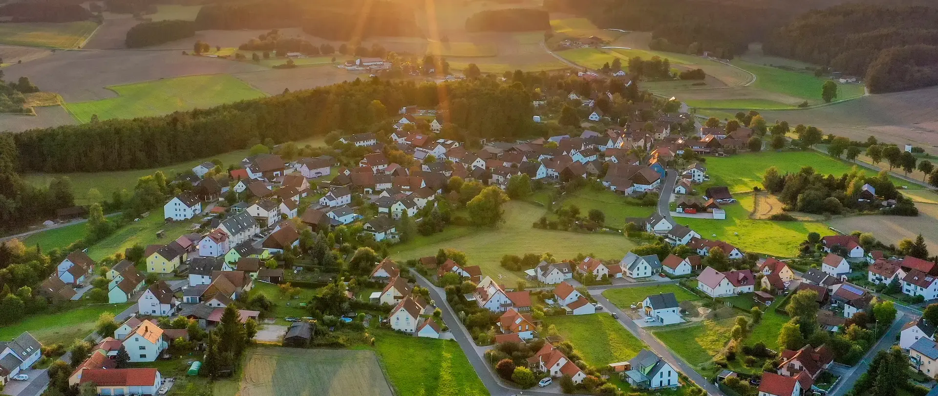 Ein ländliches Wohngebiet von oben aufgenommen mit einer Drohne. Die Sonne geht unter