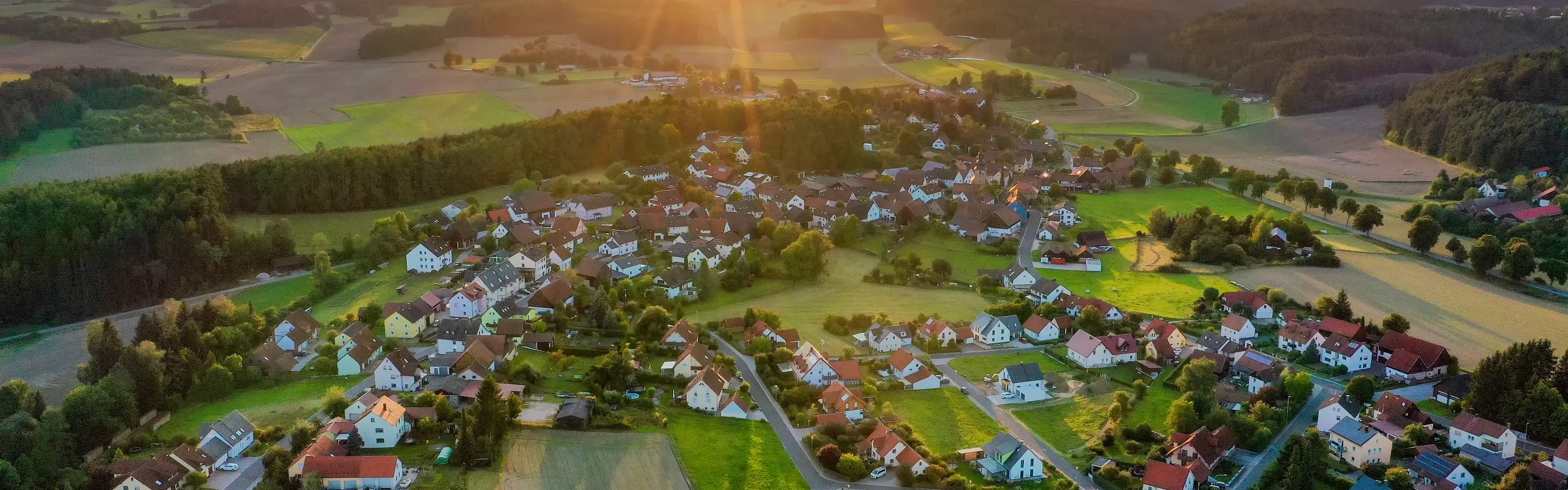 Ein ländliches Wohngebiet von oben aufgenommen mit einer Drohne. Die Sonne geht unter