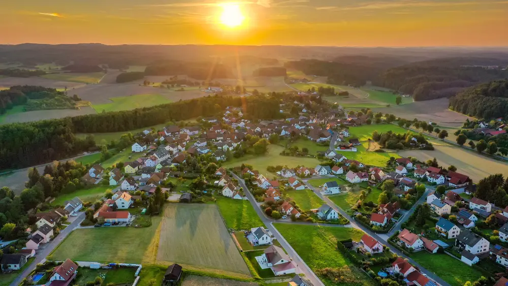 Ein ländliches Wohngebiet von oben aufgenommen mit einer Drohne. Die Sonne geht unter