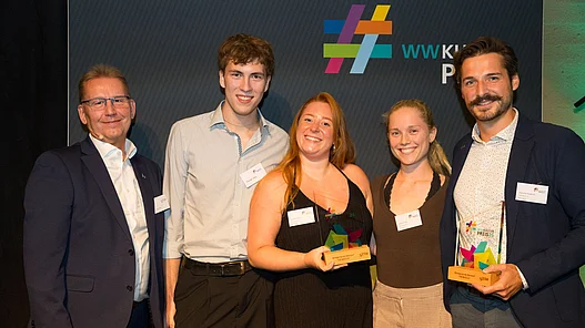 Platz 4: Musical The Batz Nenndorf Gruppenfoto vor einer Fotowand von Vereinsmitgliedern des Musical The Batz mit dem 4. Hauptpreis des WWKulturpreis26.