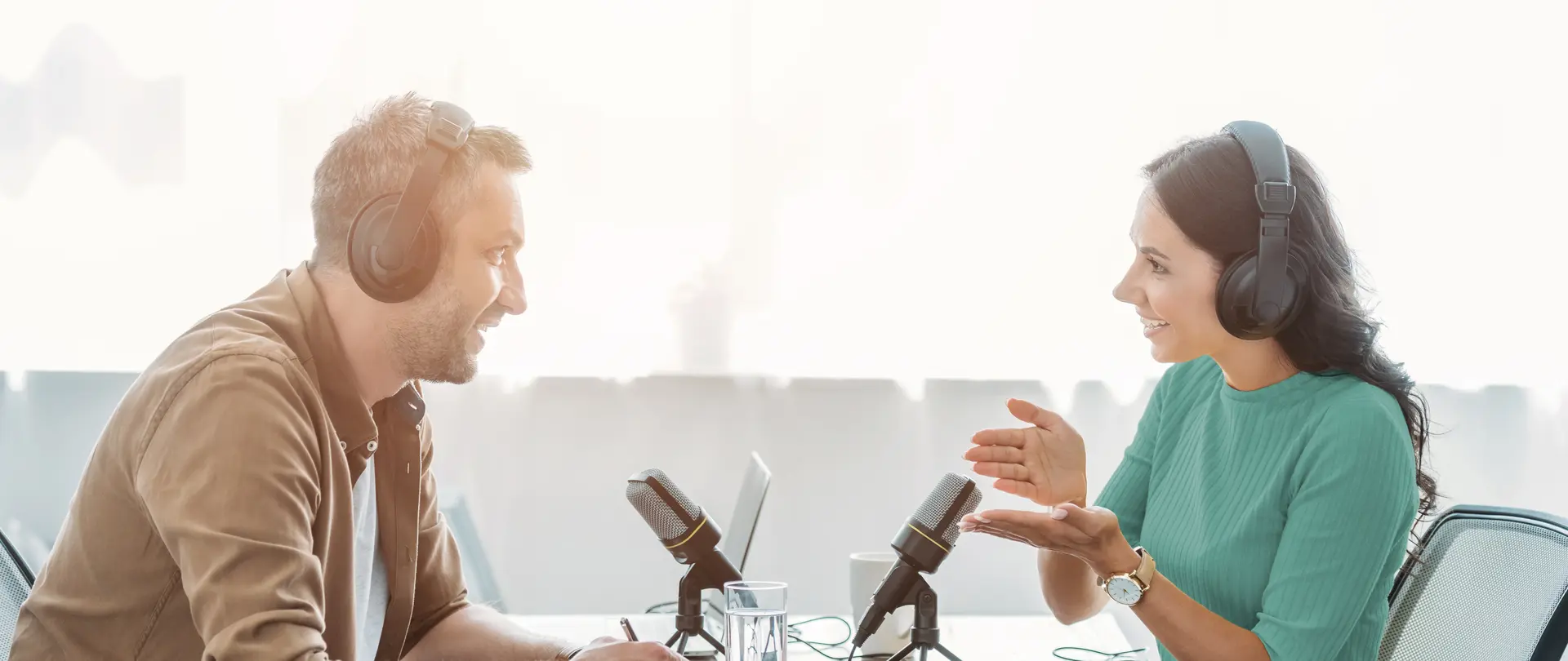 Ein Mann und eine Frau sitzen sich gegenüber und nehmen einen Podcast auf