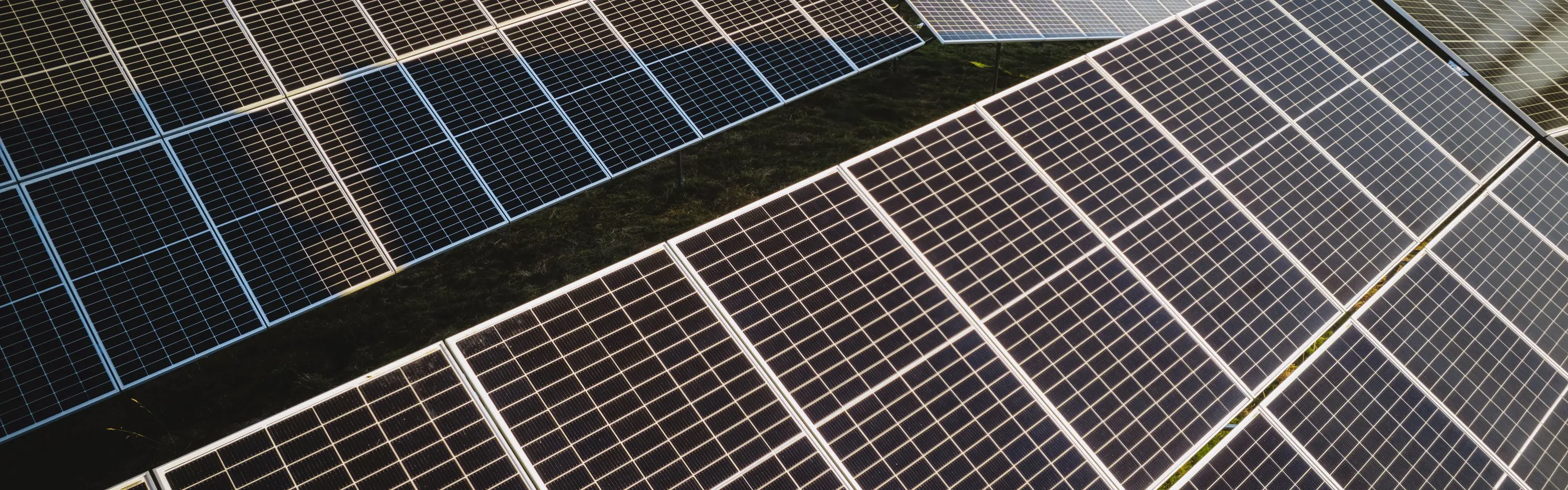 Ein großer Solarpark mit vielen Photovoltaikanlagen befindet sich auf einem Feld in der Sonne.