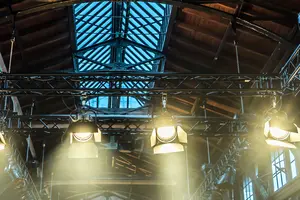 Eine Lagerhalle wird durch vier Scheinwerfer angeleuchtet.