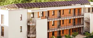 Ein modernes Mehrfamilienhaus im Grünen mit Photovoltaikanlagen auf dem flachen Gründach