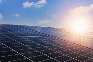 Eine große Fläche mit Solarpanels wird von Sonnenlicht bestrahlt – Energiequelle für E-Mobilität.