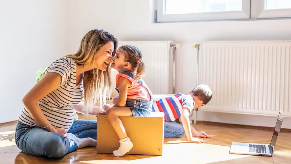 Mutter spielt mit ihren Kindern in einem Raum vor Heizkörpern