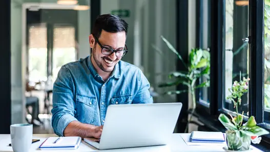 Eine Person arbeitet am Laptop in einem modernen Büro – Symbol für digitale Steuerung von Ladeinfrastruktur.