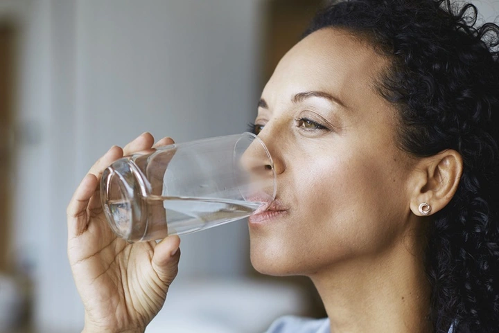 Frau trinkt Wasser aus einem Glas.