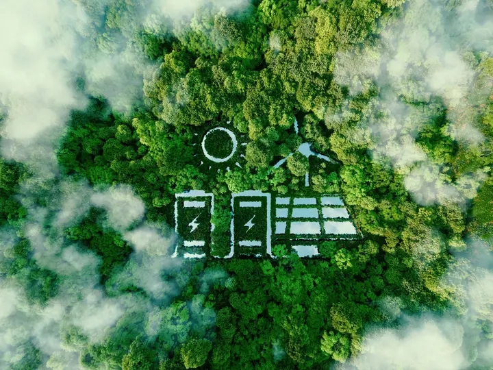Eine Luftaufnahme zeigt Wald mit Symbolen für Solarenergie und Batteriespeicher zwischen den Bäumen.