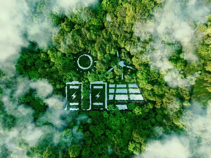 Eine Luftaufnahme zeigt Wald mit Symbolen für Solarenergie und Batteriespeicher zwischen den Bäumen.