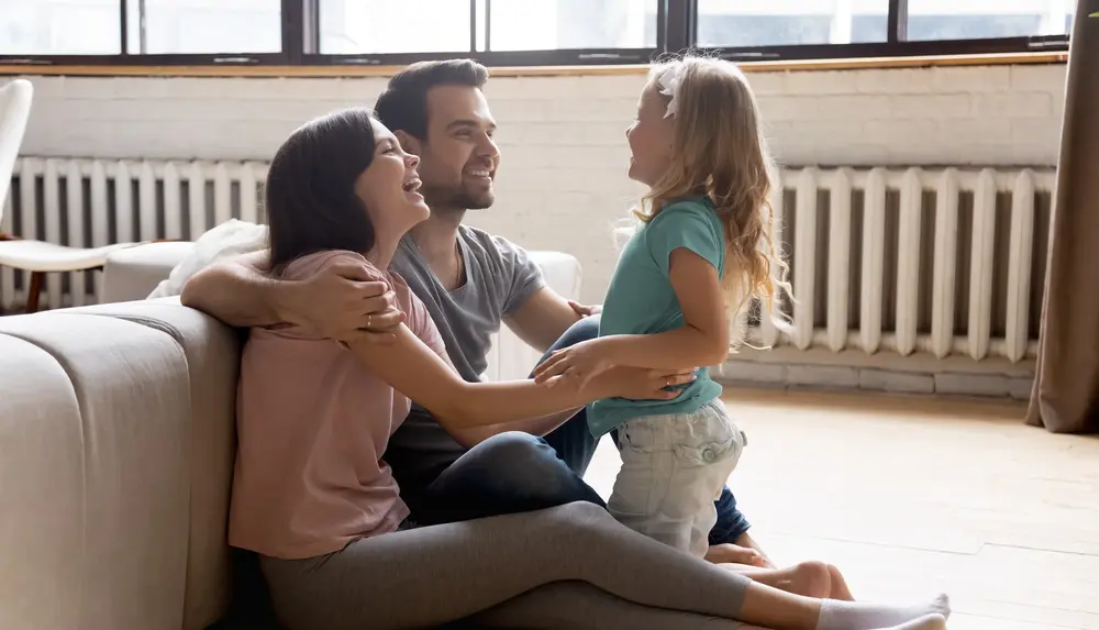 Familie mit Kind sitzend vor einer Heizung