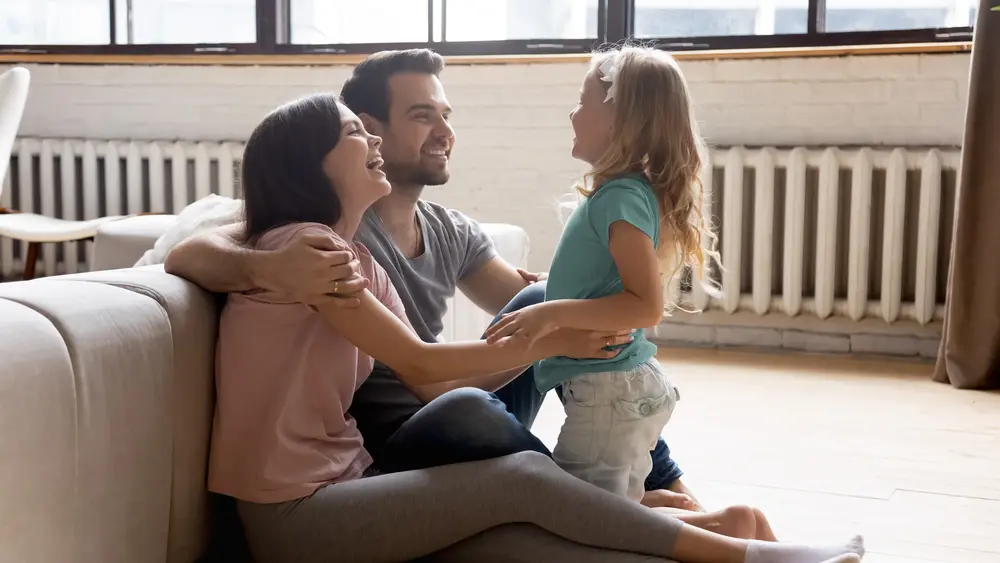 Familie mit Kind sitzend vor einer Heizung