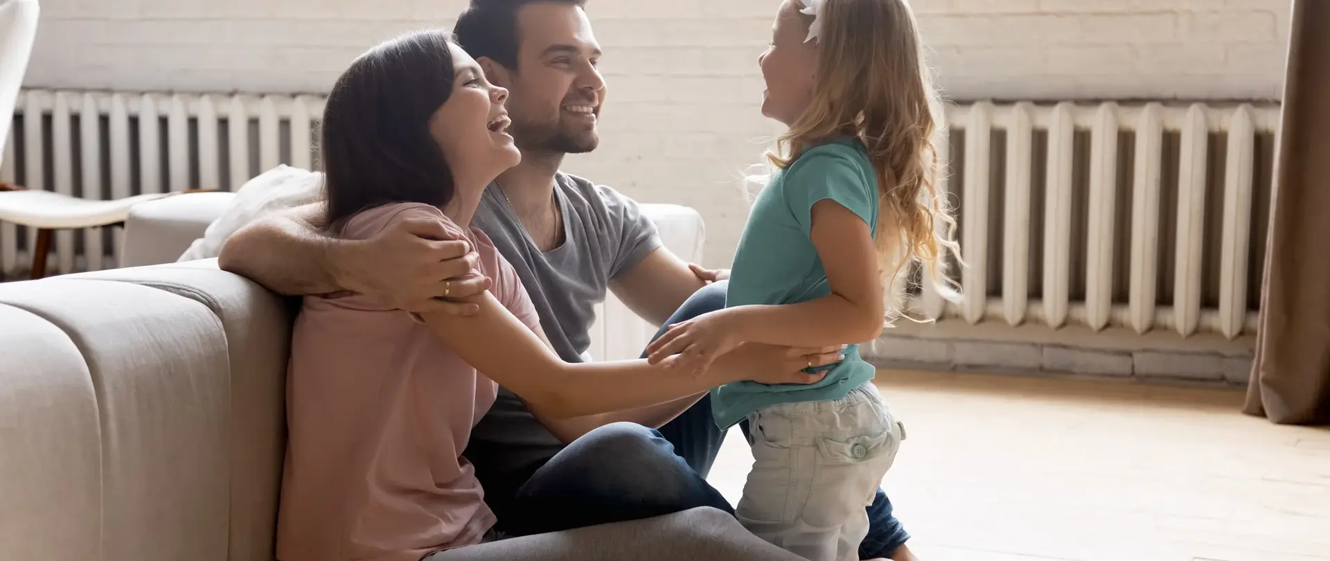 Familie mit Kind sitzend vor einer Heizung