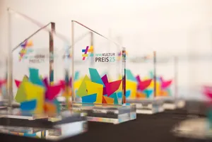 WWKulturpreis Preise Preisverleihung Mehrere Preise des WWKulturPreises stehen auf einem schwarzen Tisch. Die Preise sind aus Plexiglas und mit dem WWKulturpreis Logo versehen
