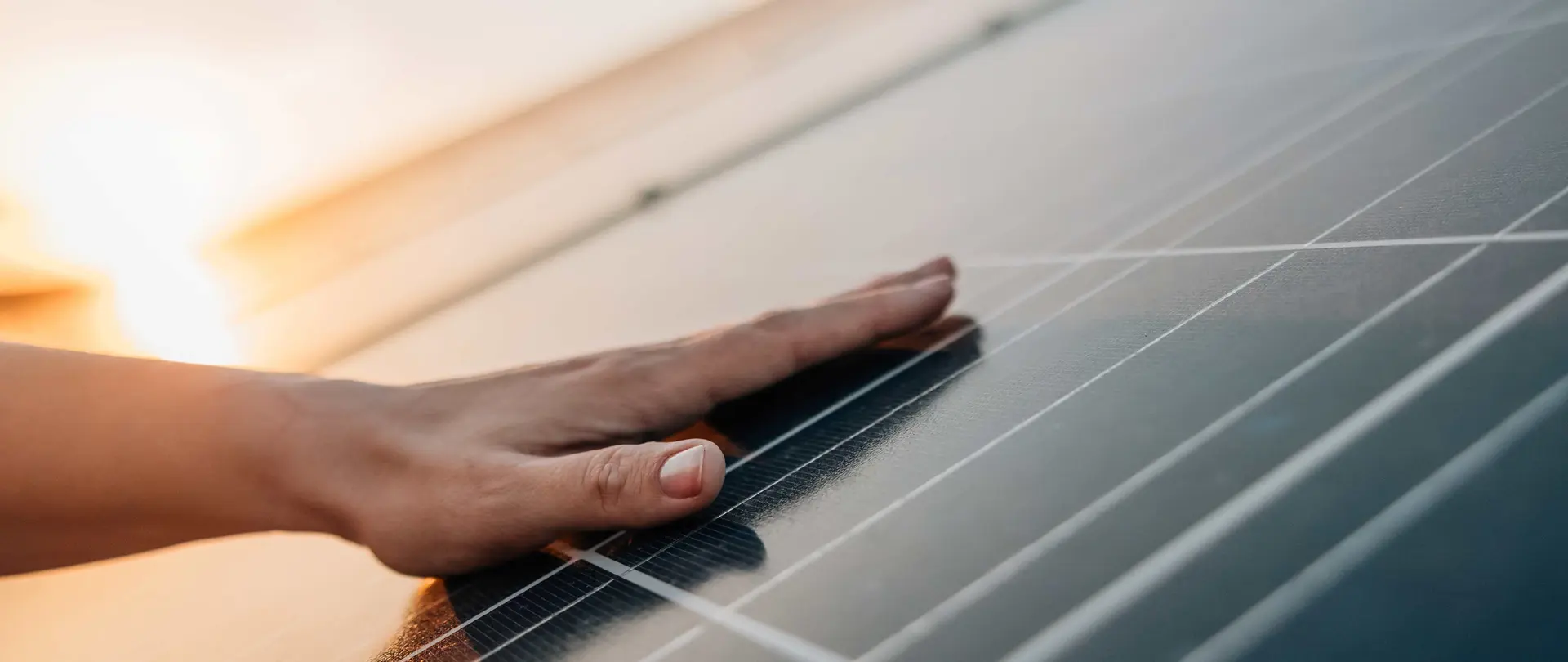 Eine Mann liegt flach auf einem Photovoltaikmodul während im Hintergrund die Sonne untergeht.