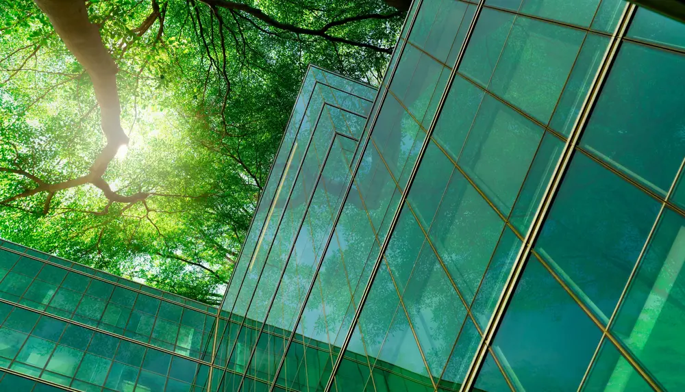 Ein Glashaus wird aus der Froschperspektive fotografiert und man sieht die Baumkronen über dem Gebäude.
