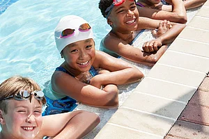 Westfalen Weser Sport Sponsoring Man sieht Kinder mit Schwimmbrillen lächelnd am Beckenrand