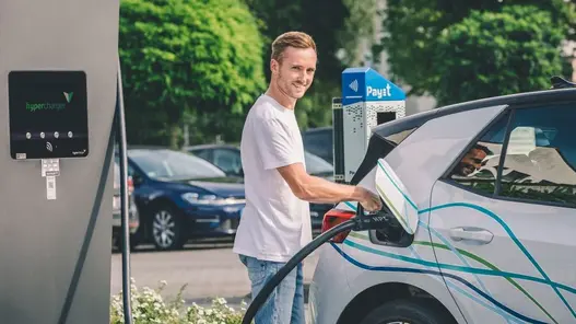 Ein Mann lädt ein Elektroauto an einer Schnelladesäule