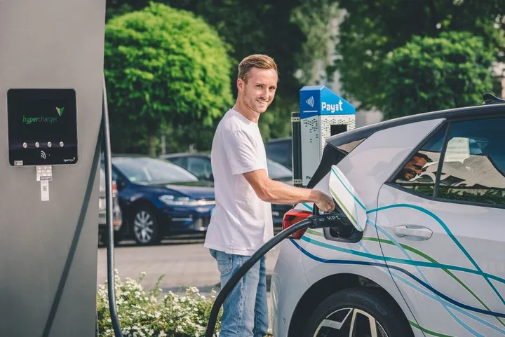 Ein Mann lädt ein Elektroauto an einer Schnelladesäule