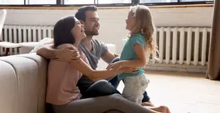 Familie sitzt im Wohnzimmer vor Heizkörpern