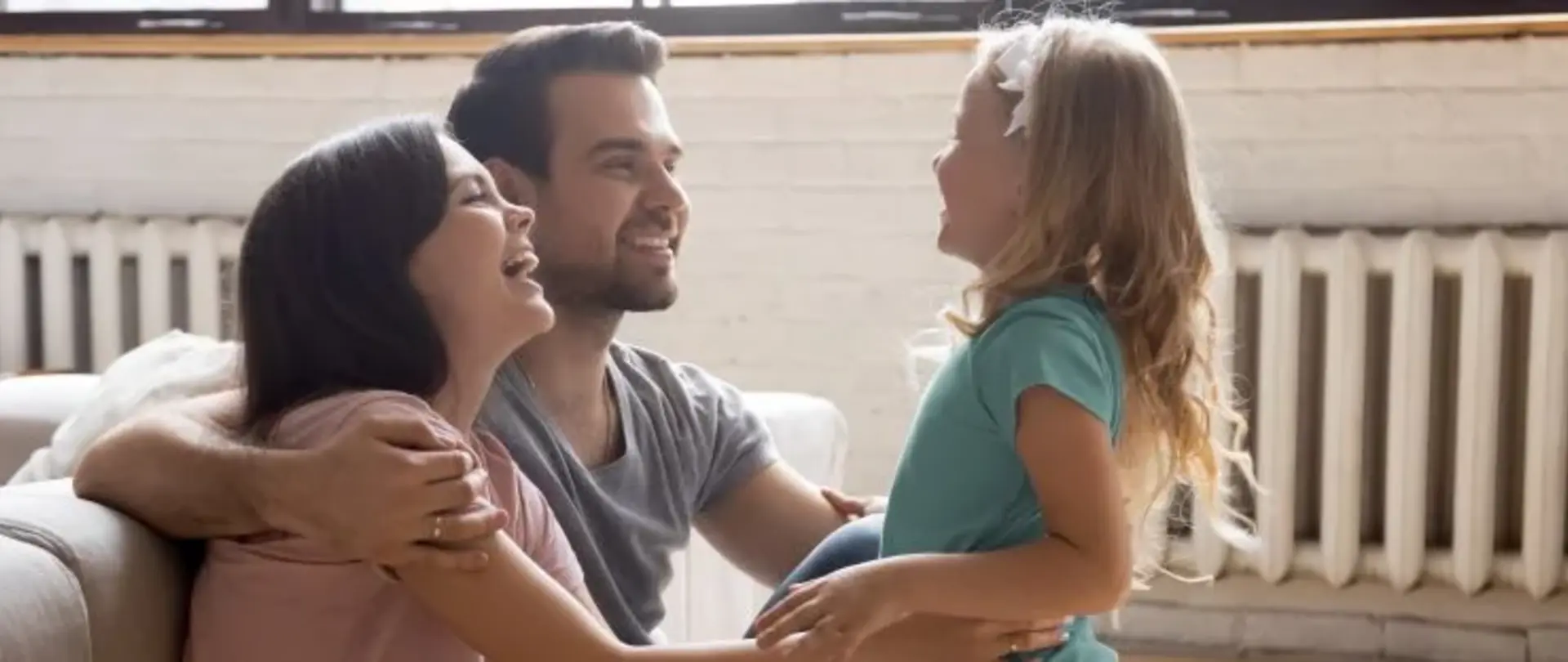 Familie sitzt im Wohnzimmer vor Heizkörpern