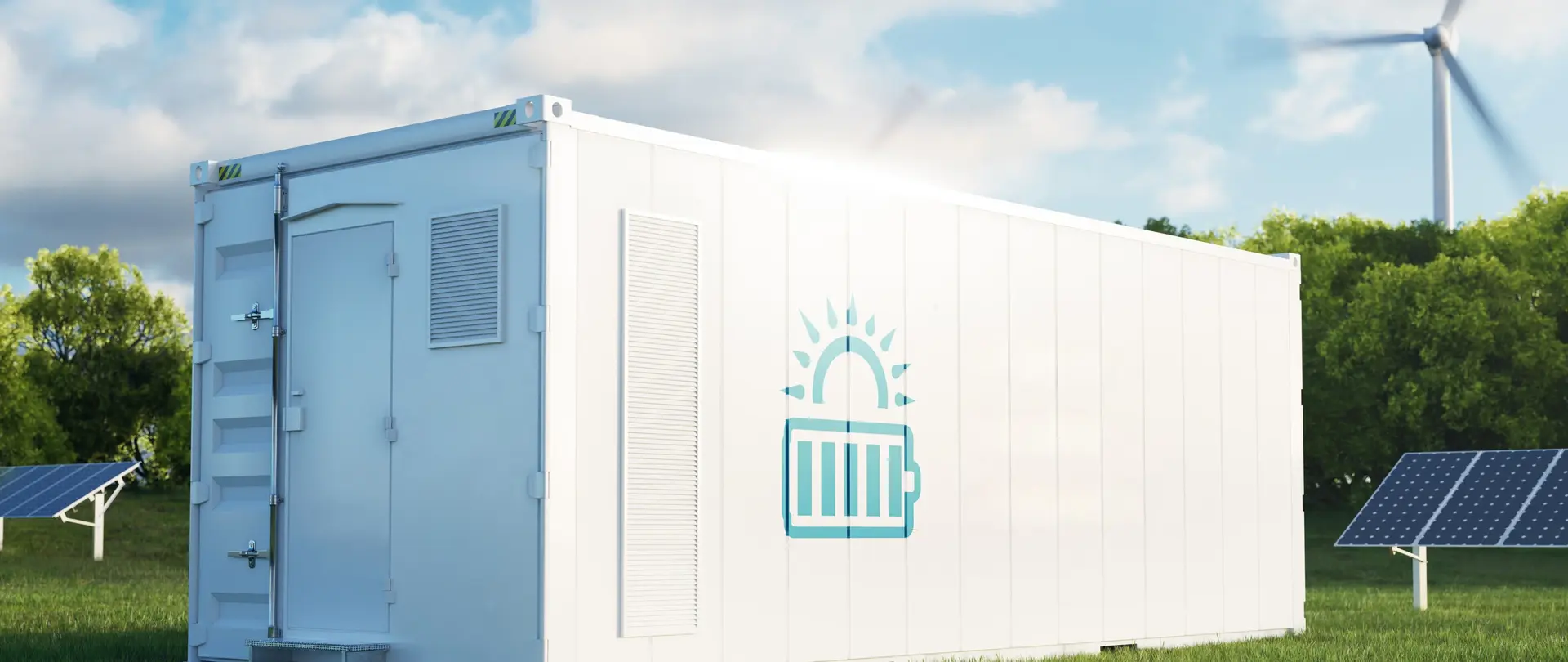Ein weißer Batteriegroßspeicher mit steht vor Solarpaneelen und einem Windrad auf einer Wiese.