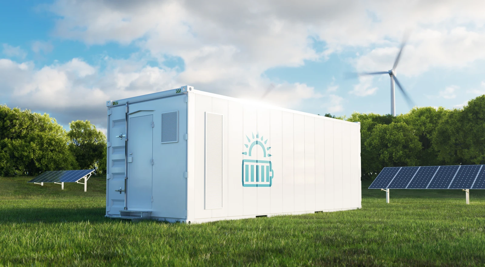 Ein weißer Batteriegroßspeicher mit steht vor Solarpaneelen und einem Windrad auf einer Wiese.