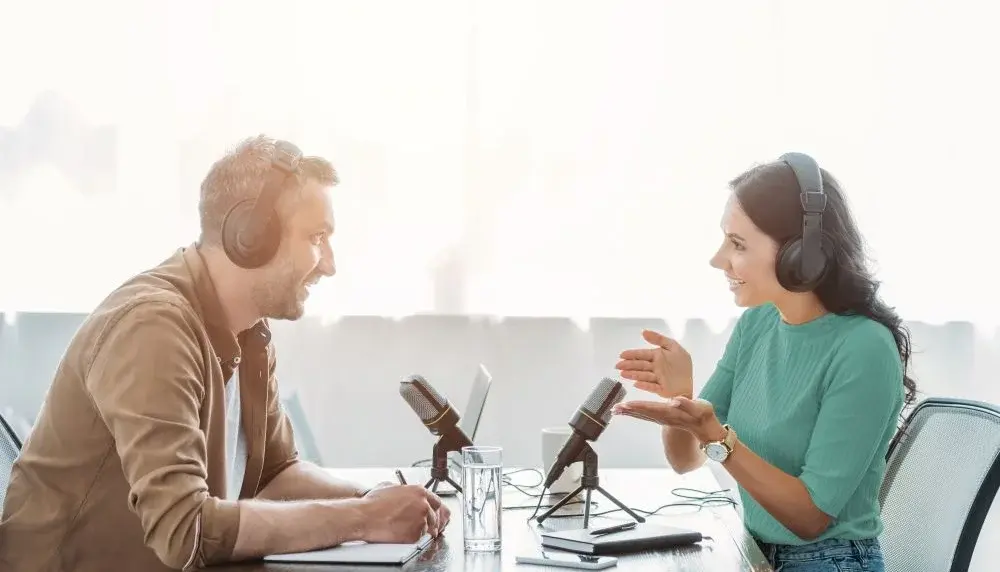 Ein Mann und eine Frau sitzen sich gegenüber und nehmen podcast auf, mit Technik Equipment