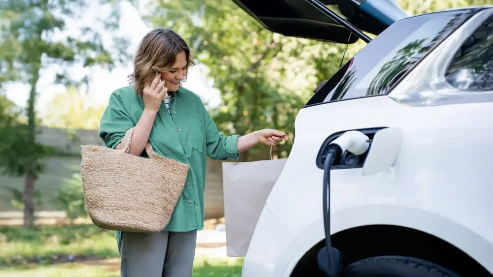 Eine Frau lädt ihr E-Auto während eines Einkaufs an einer Schnellladesäule
