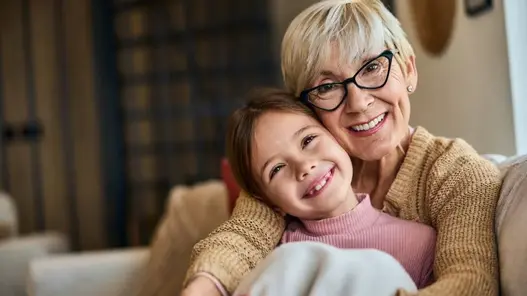 Oma und Enkelkind kuscheln glücklich auf dem Sofa
