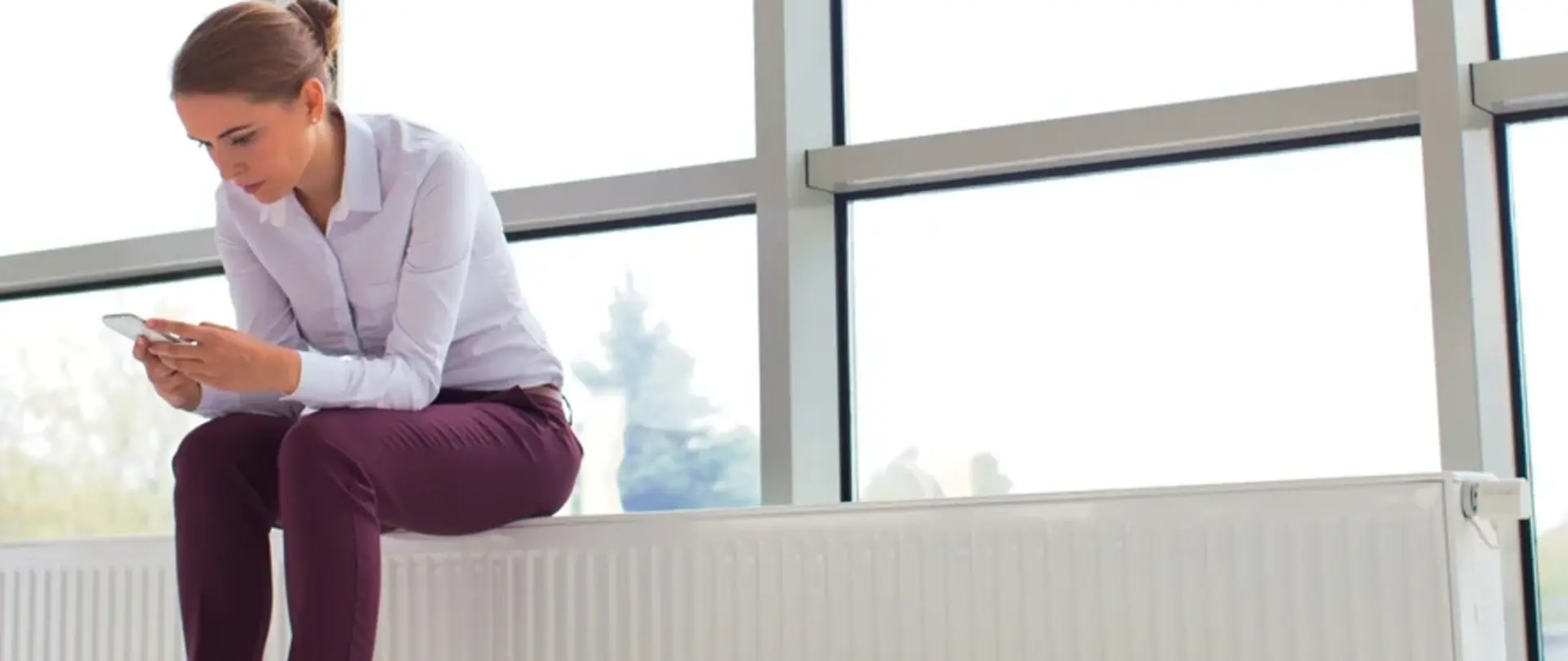 Frau sitzt auf einer Heizung