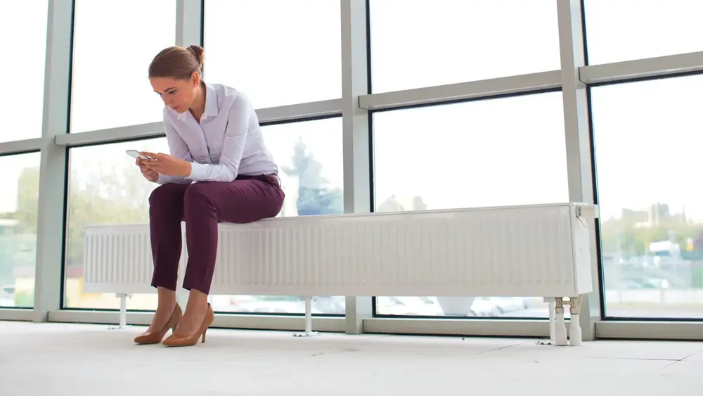 Frau sitzt auf einer Heizung