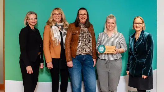 Fünf lächelnde Frauen stehen vor einem großen Display von Westfalen Weser. Eine davon hält den Preis in der Hand.