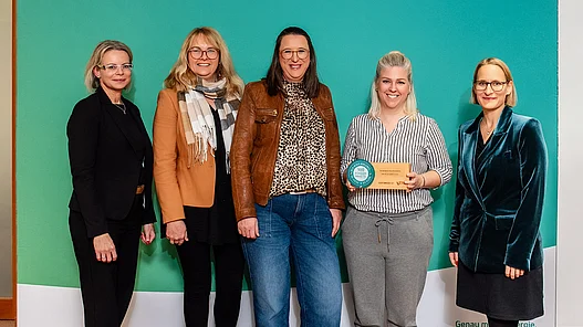 Fünf lächelnde Frauen stehen vor einem großen Display von Westfalen Weser. Eine davon hält den Preis in der Hand.
